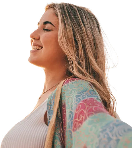 Person smiling outdoors under a bright sky